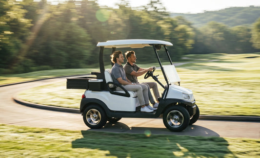 A white electric golf cart driving along a golf course cart path in a panning shot, the background blurred with motion to show speed
